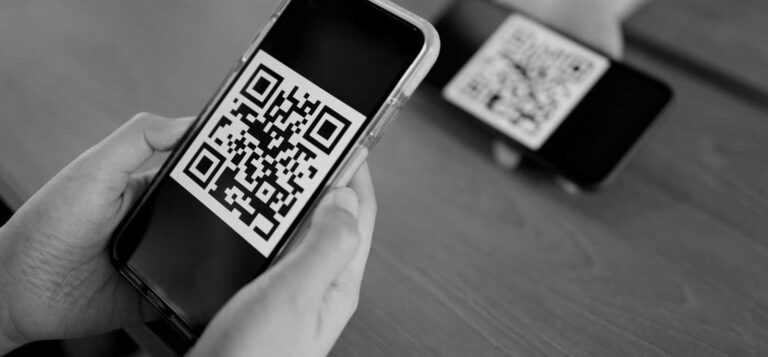 China's digital payment systems, enabling direct-to-consumer trading. Black and white photo of hands holding a personal device (iPhone) and scanning a QR code for payments.